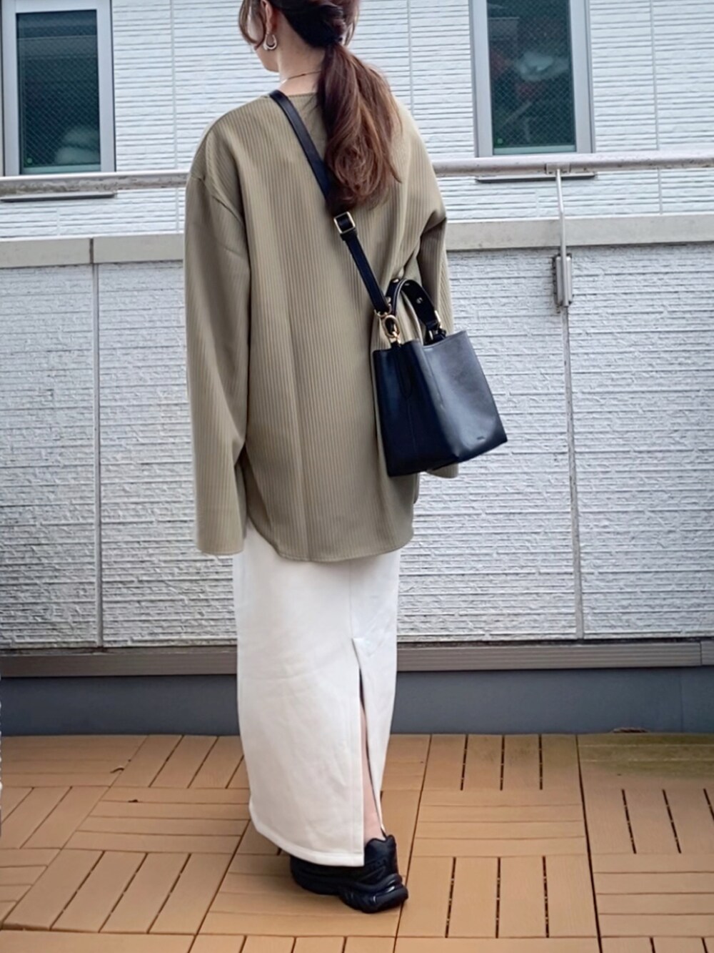 グリーン系のTシャツ/カットソー、ホワイト系のスカート、ブラック系のショルダーバッグを着用したレディースの秋コーディネートの4枚目の写真