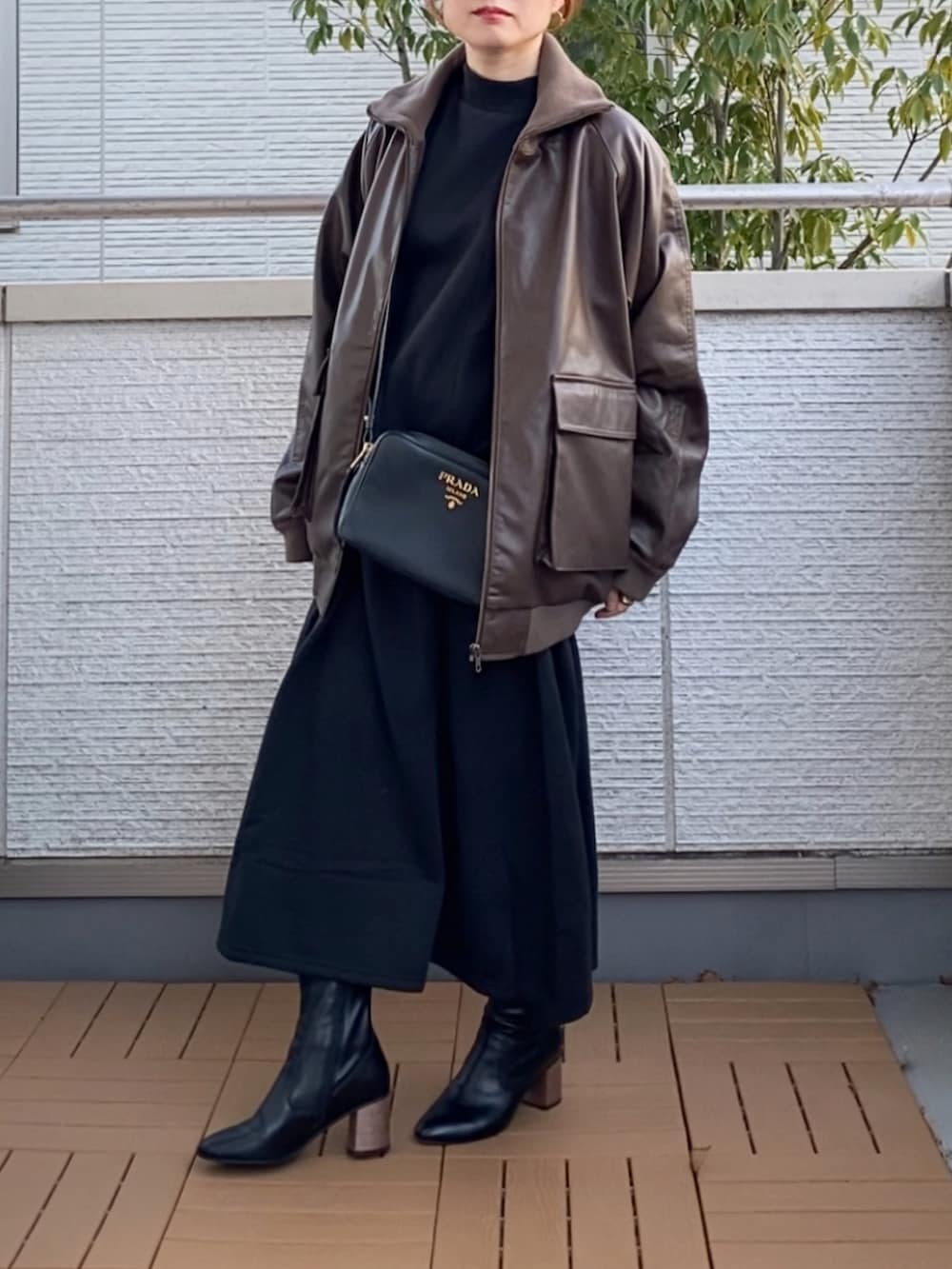 ブラック系のワンピース、ブラウン系のライダースジャケット、ブラック系のブーツを着用したレディースの冬コーディネートの2枚目の写真