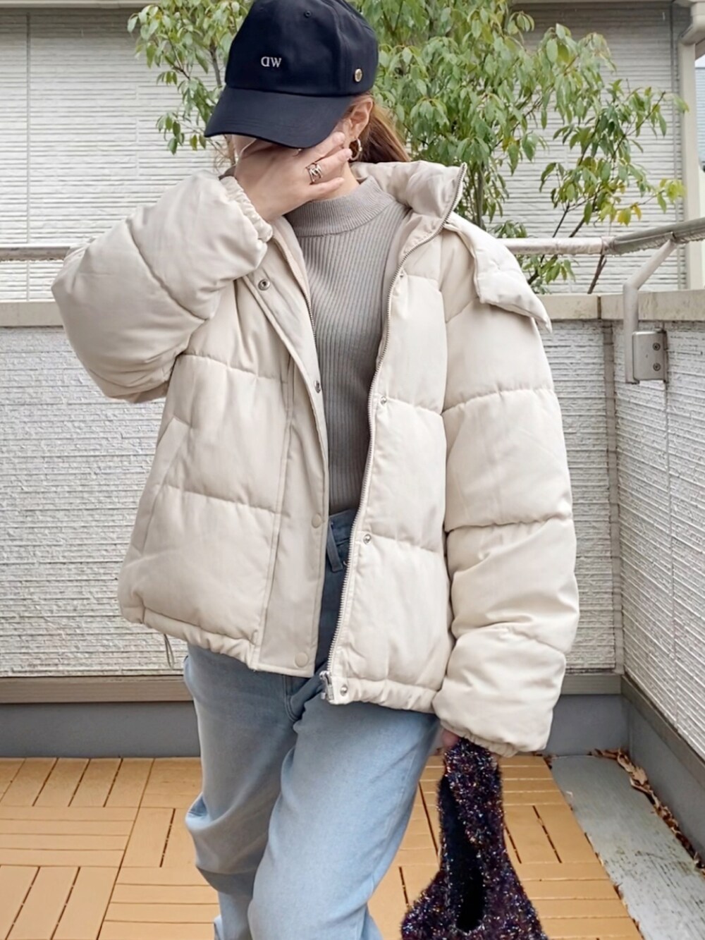 ホワイト系のダウンジャケット/コート、グレー系のニット/セーター、ブルー系のデニムパンツを着用したレディースの冬コーディネートの4枚目の写真