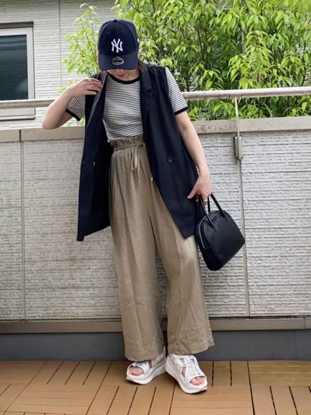 ホワイト系のTシャツ/カットソー、ブラック系のベスト、ベージュ系のその他パンツを着用したレディースの夏コーディネートの2枚目の写真