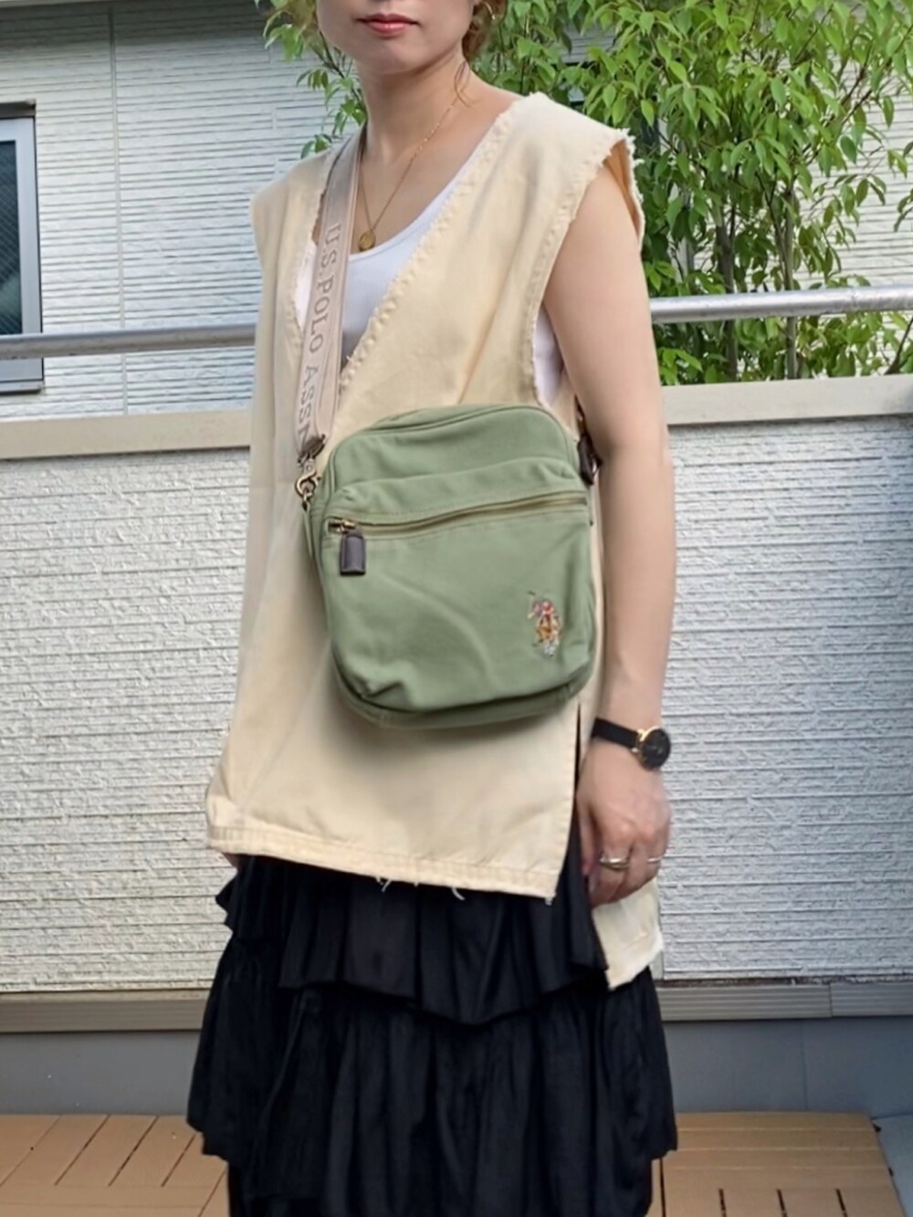 ホワイト系のベスト、ブラック系のスカート、グリーン系のショルダーバッグを着用したレディースの夏コーディネートの3枚目の写真