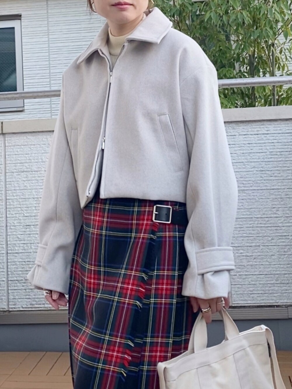 ホワイト系のブルゾン、ブラック系のスカート、ホワイト系のトートバッグを着用したレディースの秋コーディネートの3枚目の写真