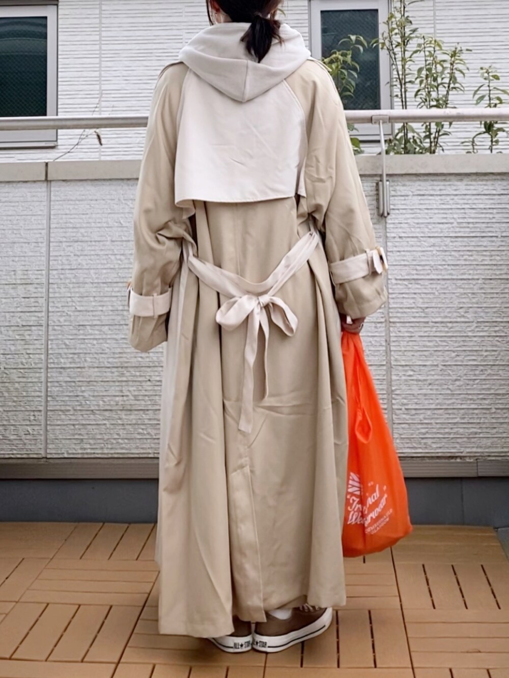 ベージュ系のトレンチコート、グレー系のパーカー、ベージュ系のパンツを着用したレディースの冬コーディネートの2枚目の写真