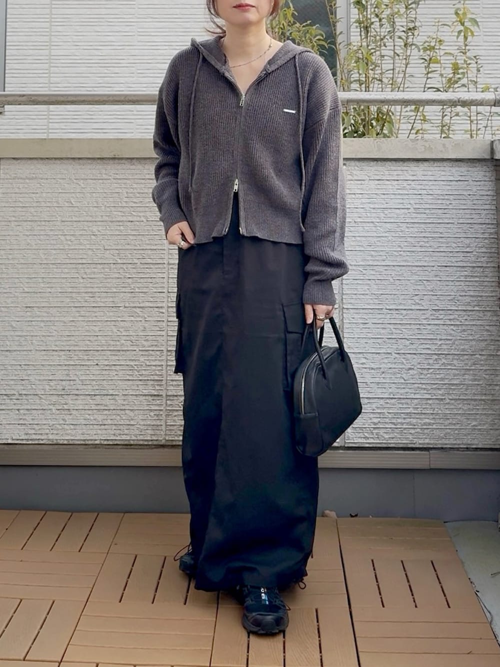 グレー系のパーカー、ブラック系のスカート、ブラック系のショルダーバッグを着用したレディースの冬コーディネートの2枚目の写真