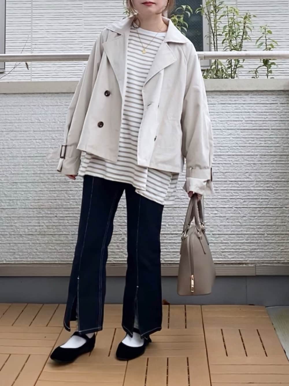 ホワイト系のトレンチコート、ベージュ系のTシャツ/カットソー、ブラック系のデニムパンツを着用したレディースの春コーディネートの2枚目の写真