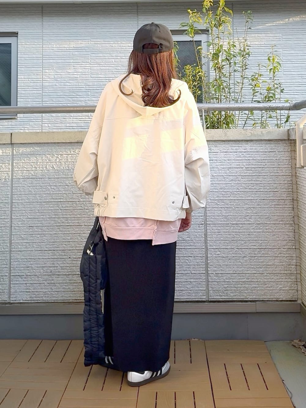 ピンク系のスウェット、ホワイト系のマウンテンパーカー、ブラック系のスカートを着用したレディースの春コーディネートの3枚目の写真