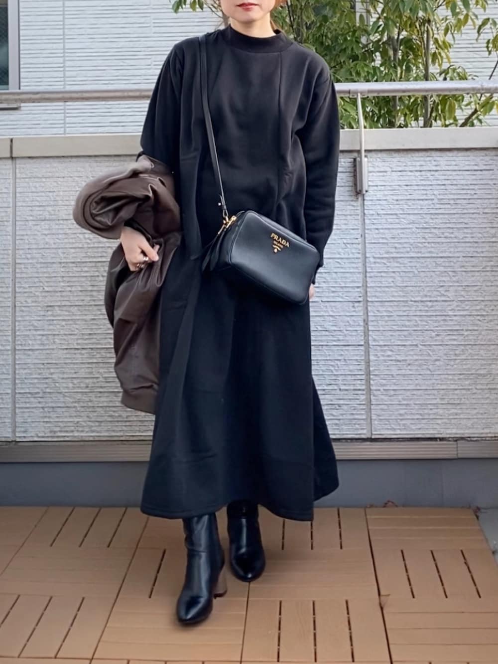 ブラック系のワンピース、ブラウン系のライダースジャケット、ブラック系のブーツを着用したレディースの冬コーディネートの3枚目の写真