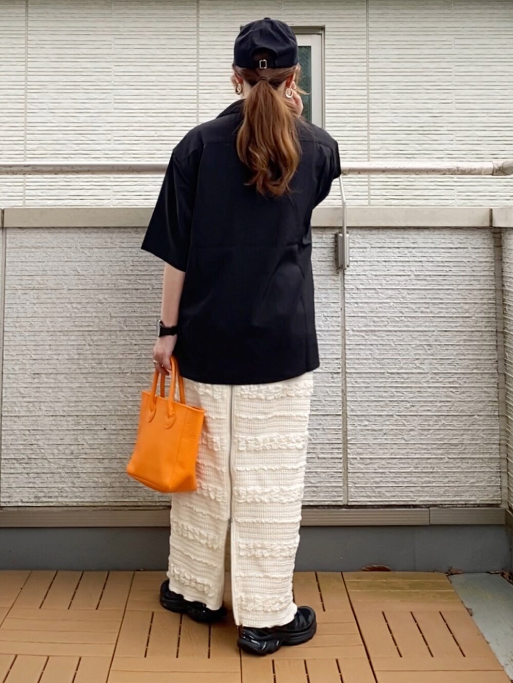 ブラック系のシャツ/ブラウス、ホワイト系のスカート、オレンジ系のトートバッグを着用したレディースの夏コーディネートの3枚目の写真