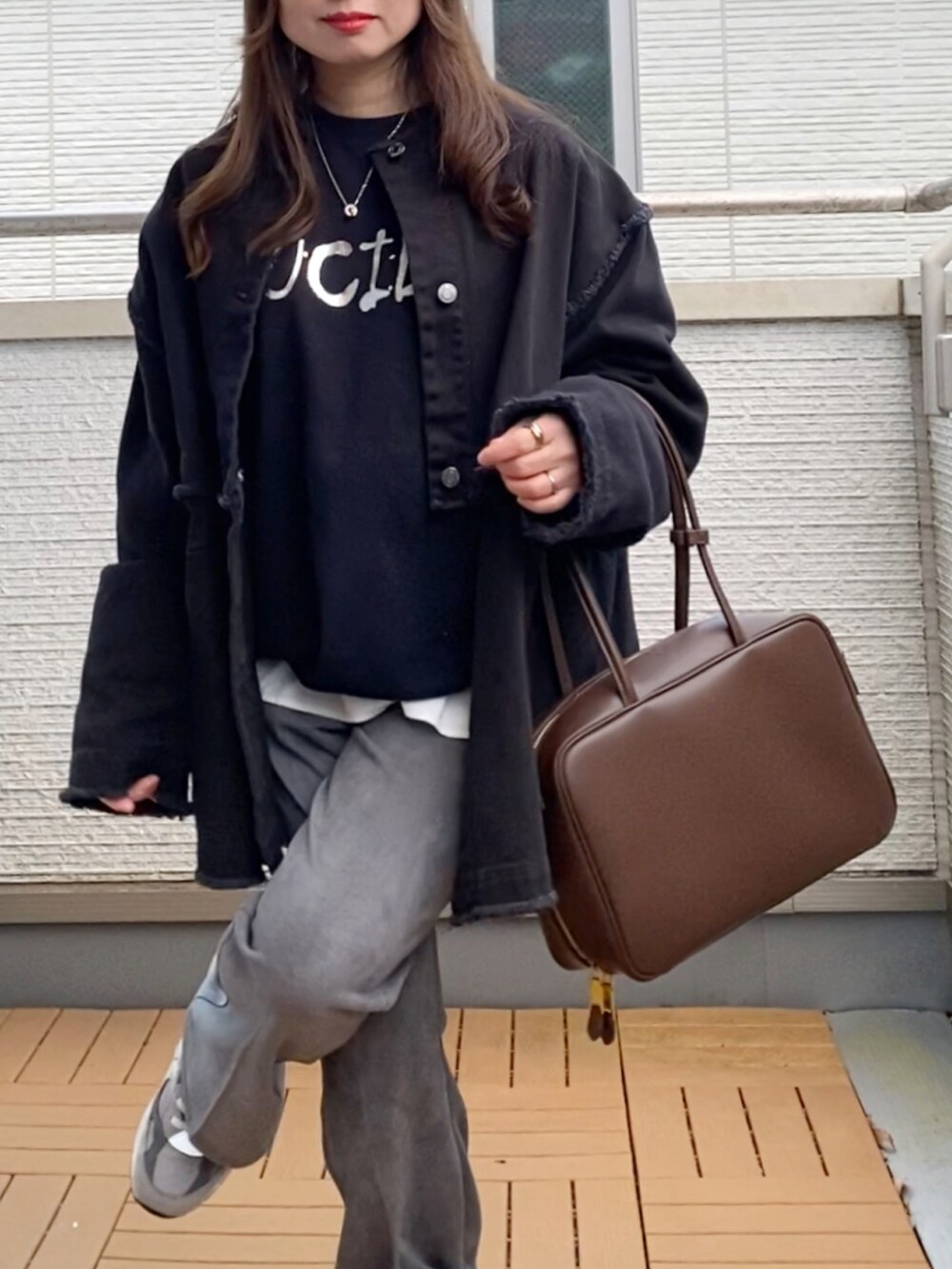 ブラック系のデニムジャケット、ブラック系のスウェット、グレー系のスラックスを着用したレディースの冬コーディネートの4枚目の写真