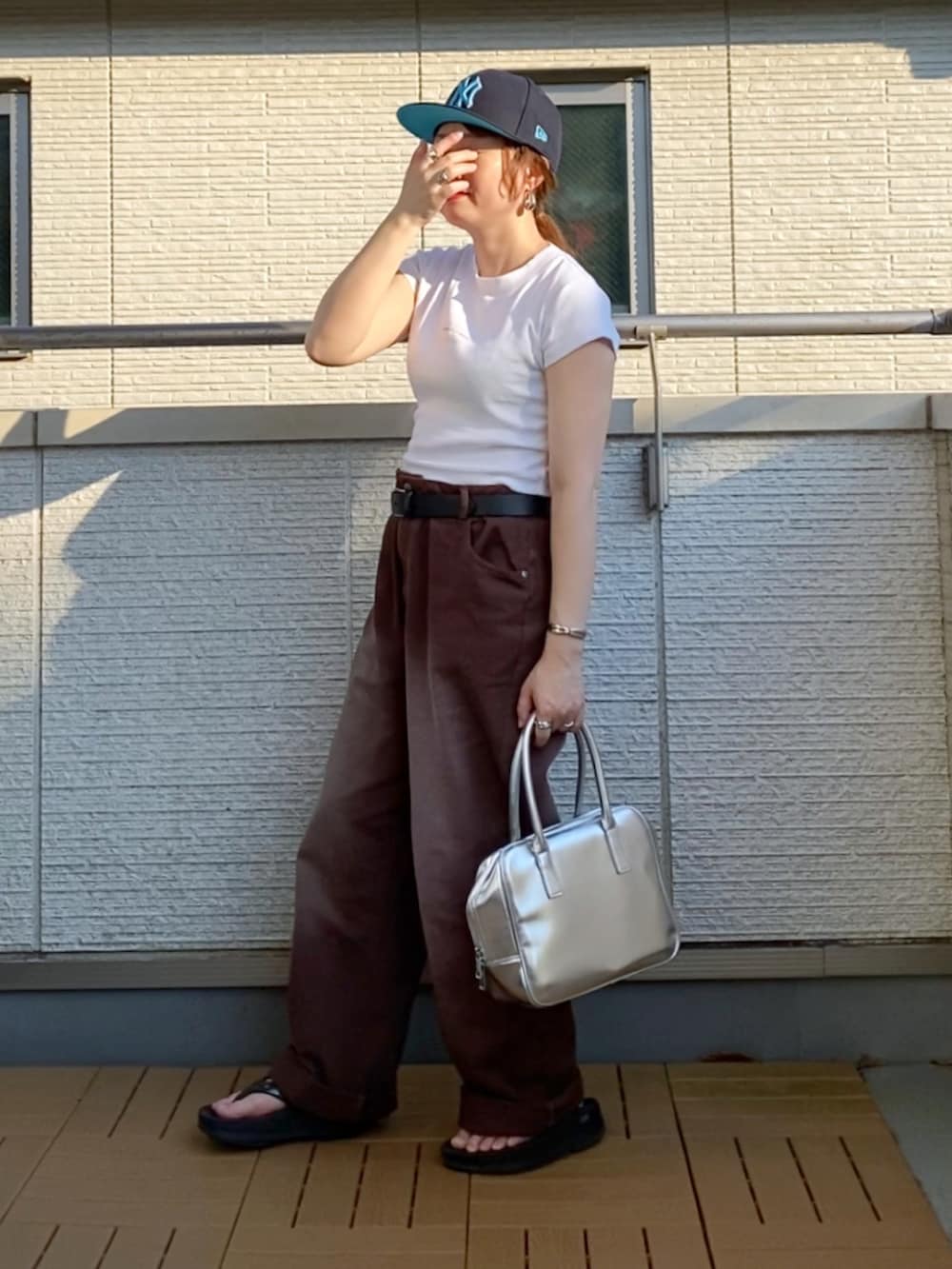 ホワイト系のTシャツ/カットソー、ブラウン系のデニムパンツ、シルバー系のボストンバッグを着用したレディースの夏コーディネートの2枚目の写真