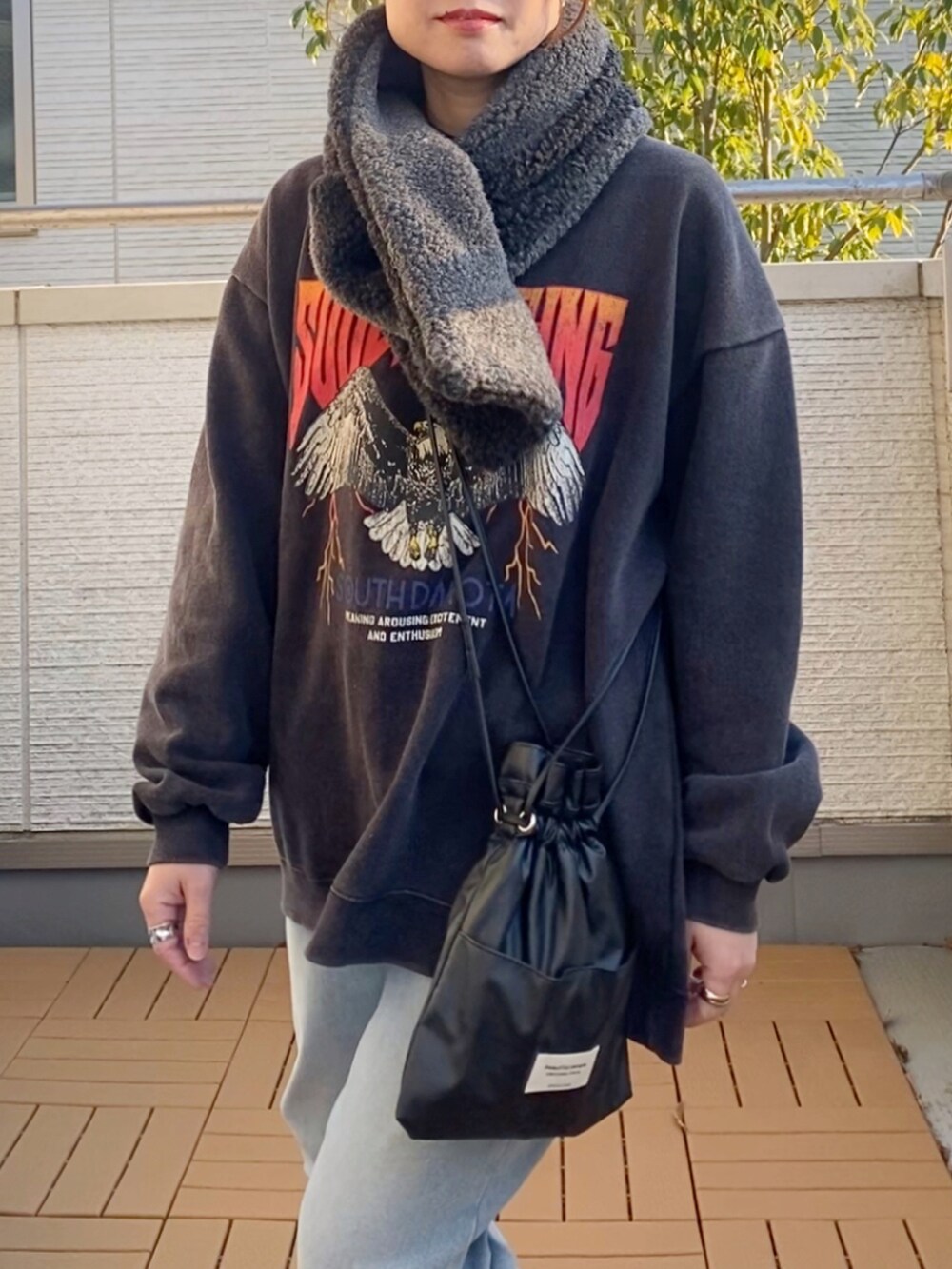 グレー系のスウェット、ブルー系のデニムパンツ、ブラック系のショルダーバッグを着用したレディースの冬コーディネートの2枚目の写真