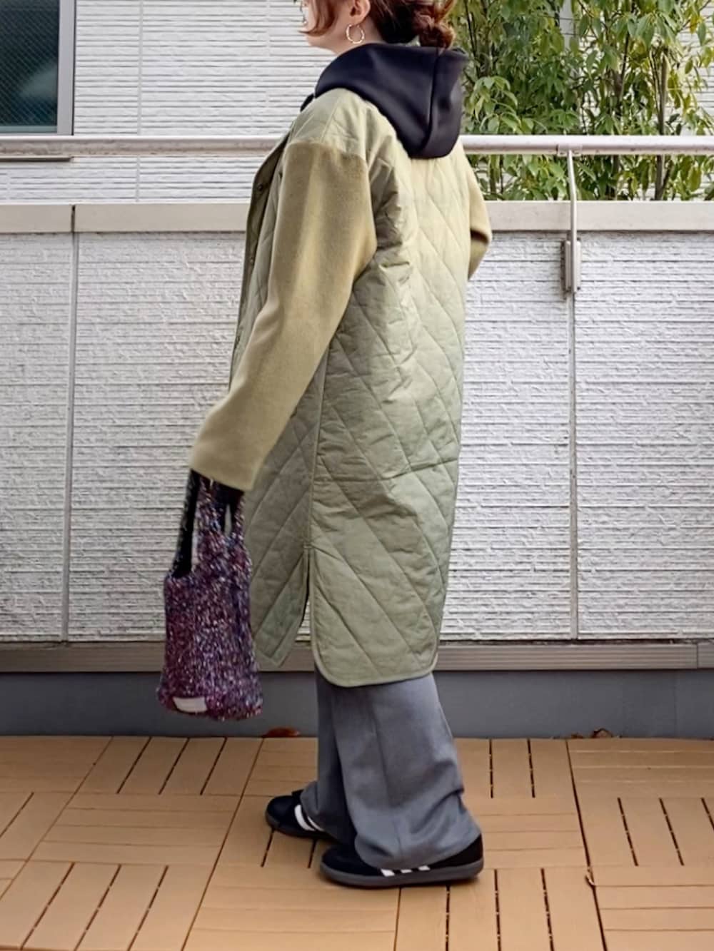 グリーン系のノーカラーコート、ブラック系のパーカー、グレー系のスラックスを着用したレディースの冬コーディネートの2枚目の写真