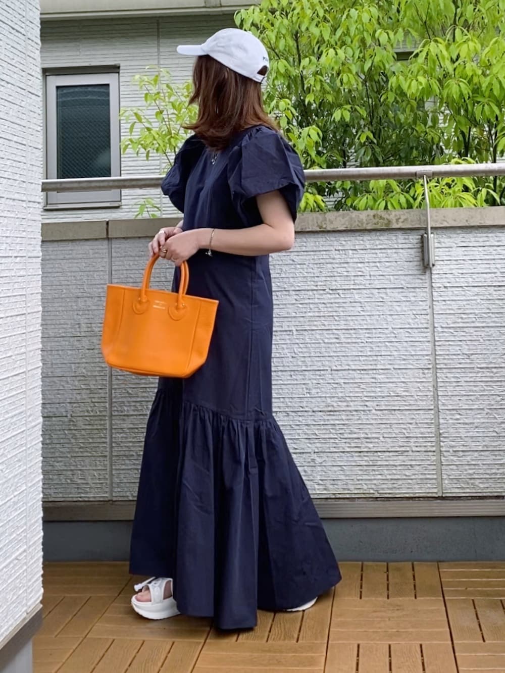 ブルー系のワンピース、オレンジ系のトートバッグ、ホワイト系のサンダルを着用したレディースの春コーディネートの3枚目の写真