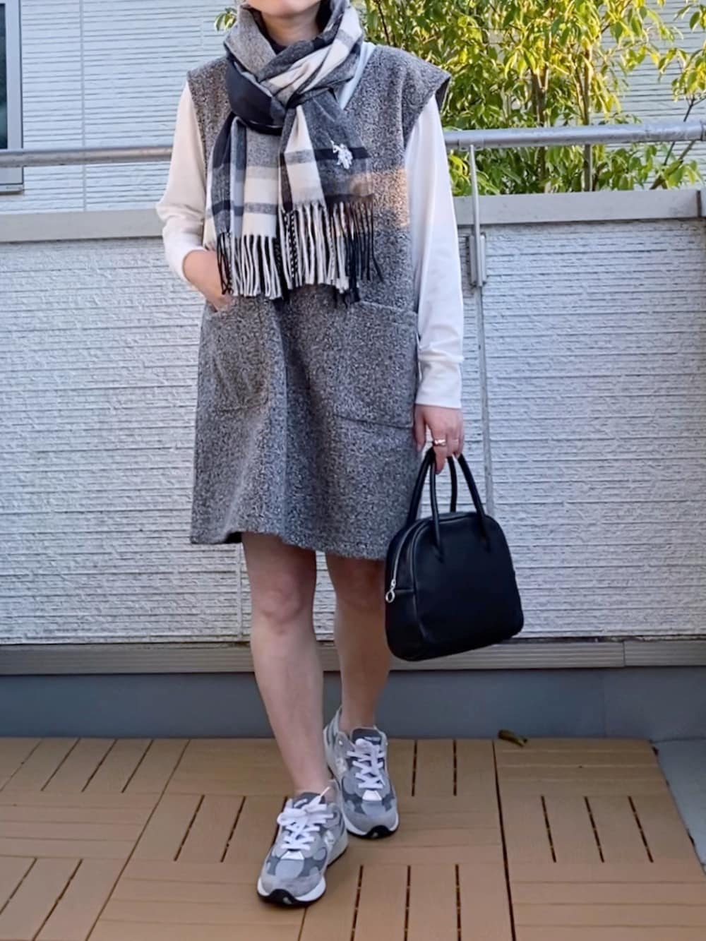 グレー系のジャンパースカート、グレー系のスニーカー、ブラック系のショルダーバッグを着用したレディースの秋コーディネートの2枚目の写真