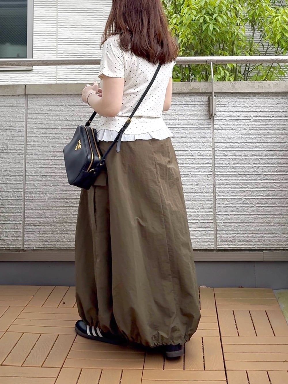 ホワイト系のTシャツ/カットソー、グリーン系のスカート、ブラック系のスニーカーを着用したレディースの春コーディネートの3枚目の写真