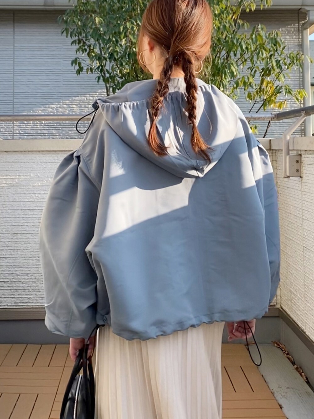 ブルー系のマウンテンパーカー、グリーン系のショルダーバッグ、ホワイト系のスニーカーを着用したレディースの春コーディネートの4枚目の写真