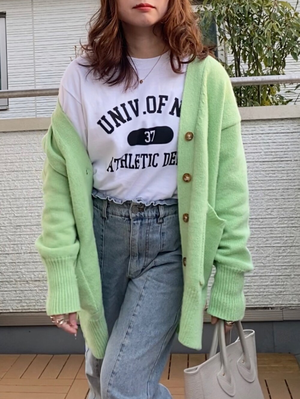 ホワイト系のTシャツ/カットソー、グリーン系のカーディガン/ボレロ、ブルー系のデニムパンツを着用したレディースの冬コーディネートの2枚目の写真