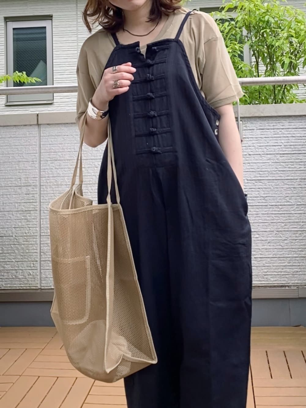 ブラック系のサロペット/オーバーオール、ベージュ系のTシャツ/カットソー、ベージュ系のエコバッグ/サブバッグを着用したレディースの夏コーディネートの2枚目の写真