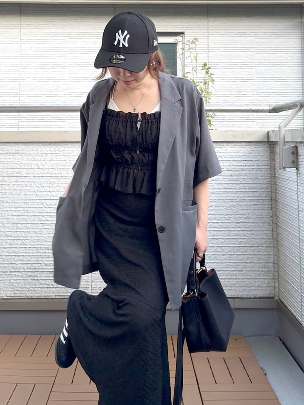 グレー系のテーラードジャケット、ブラック系のワンピース、ブラック系のショルダーバッグを着用したレディースの夏コーディネートの4枚目の写真