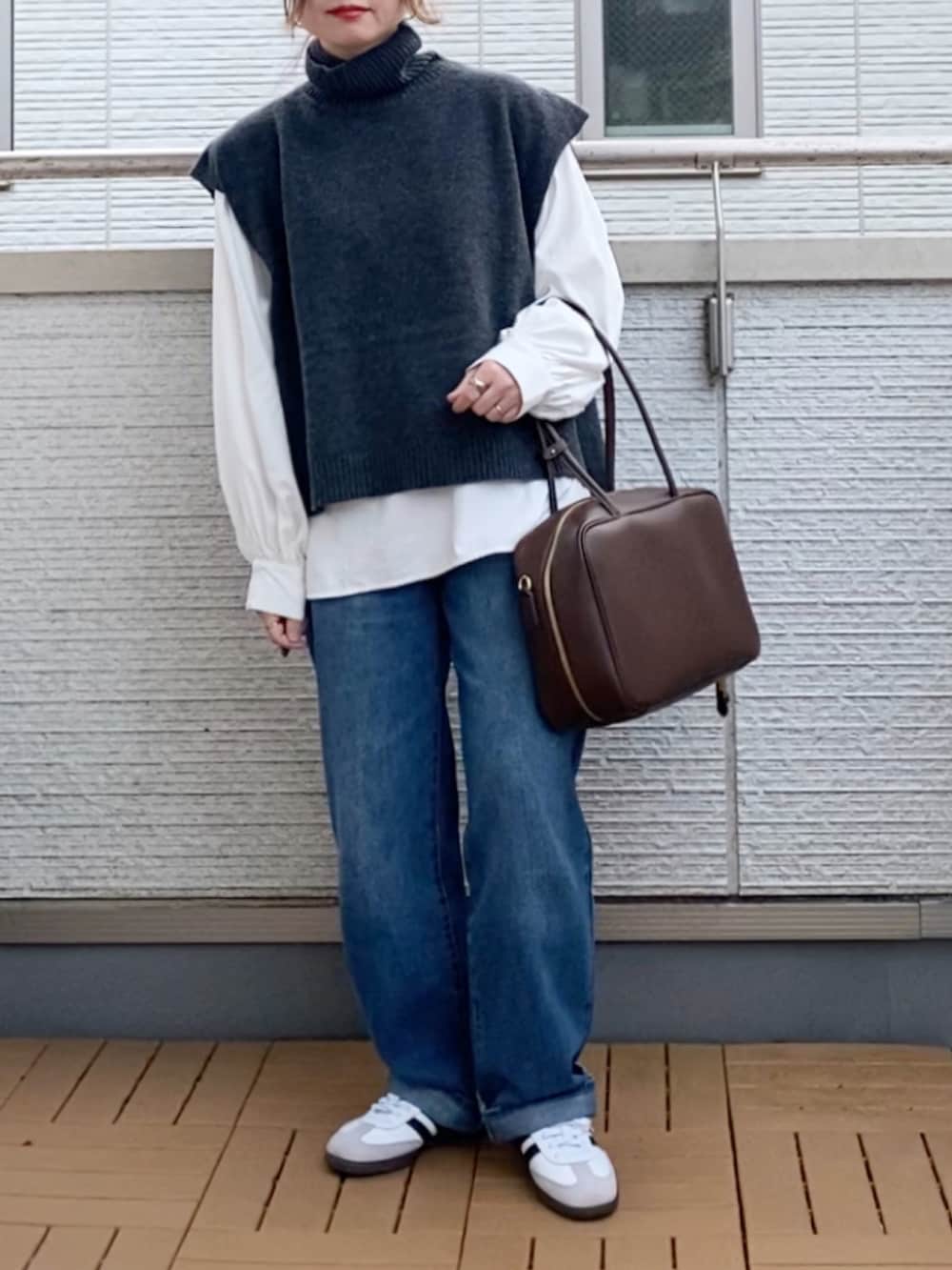 グレー系のベスト、ホワイト系のシャツ/ブラウス、ブルー系のデニムパンツを着用したレディースの冬コーディネートの2枚目の写真