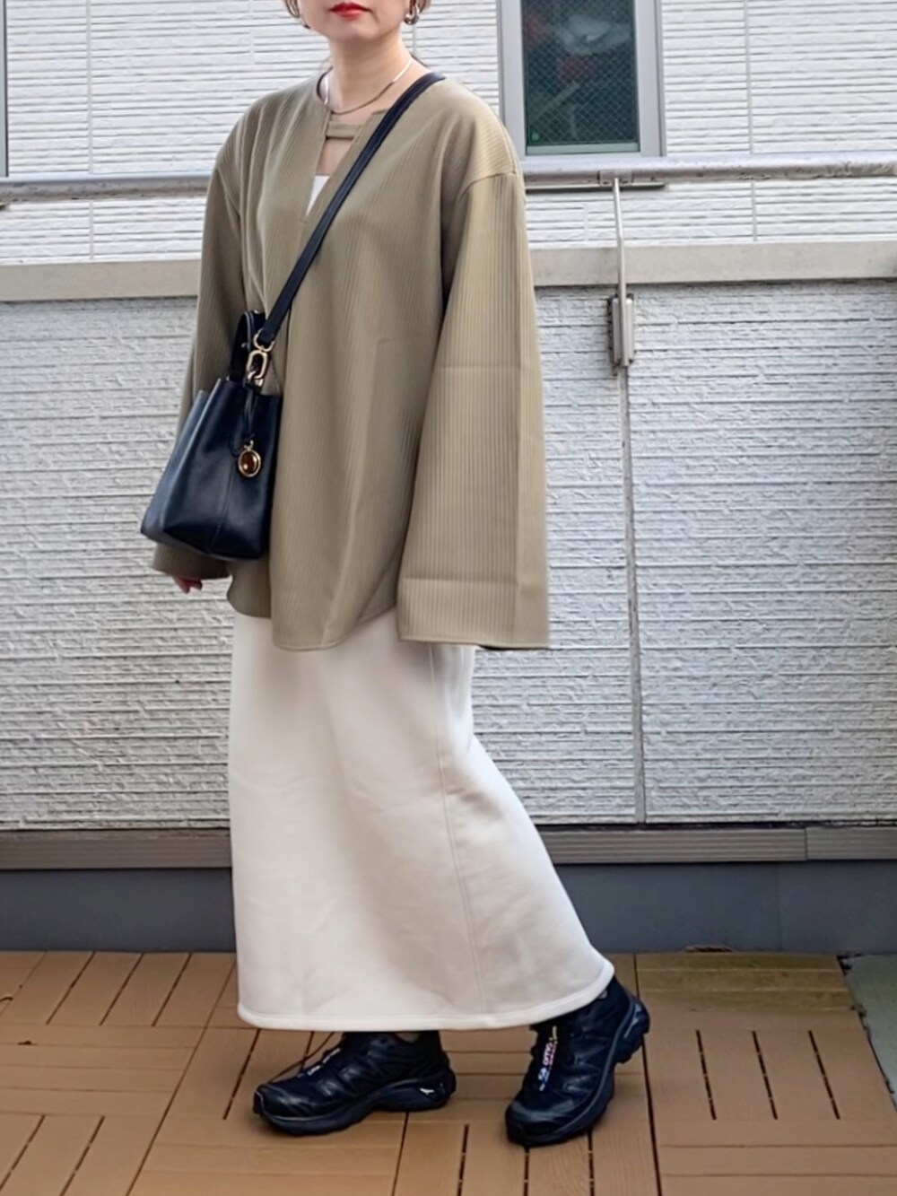 グリーン系のTシャツ/カットソー、ホワイト系のスカート、ブラック系のショルダーバッグを着用したレディースの秋コーディネートの2枚目の写真