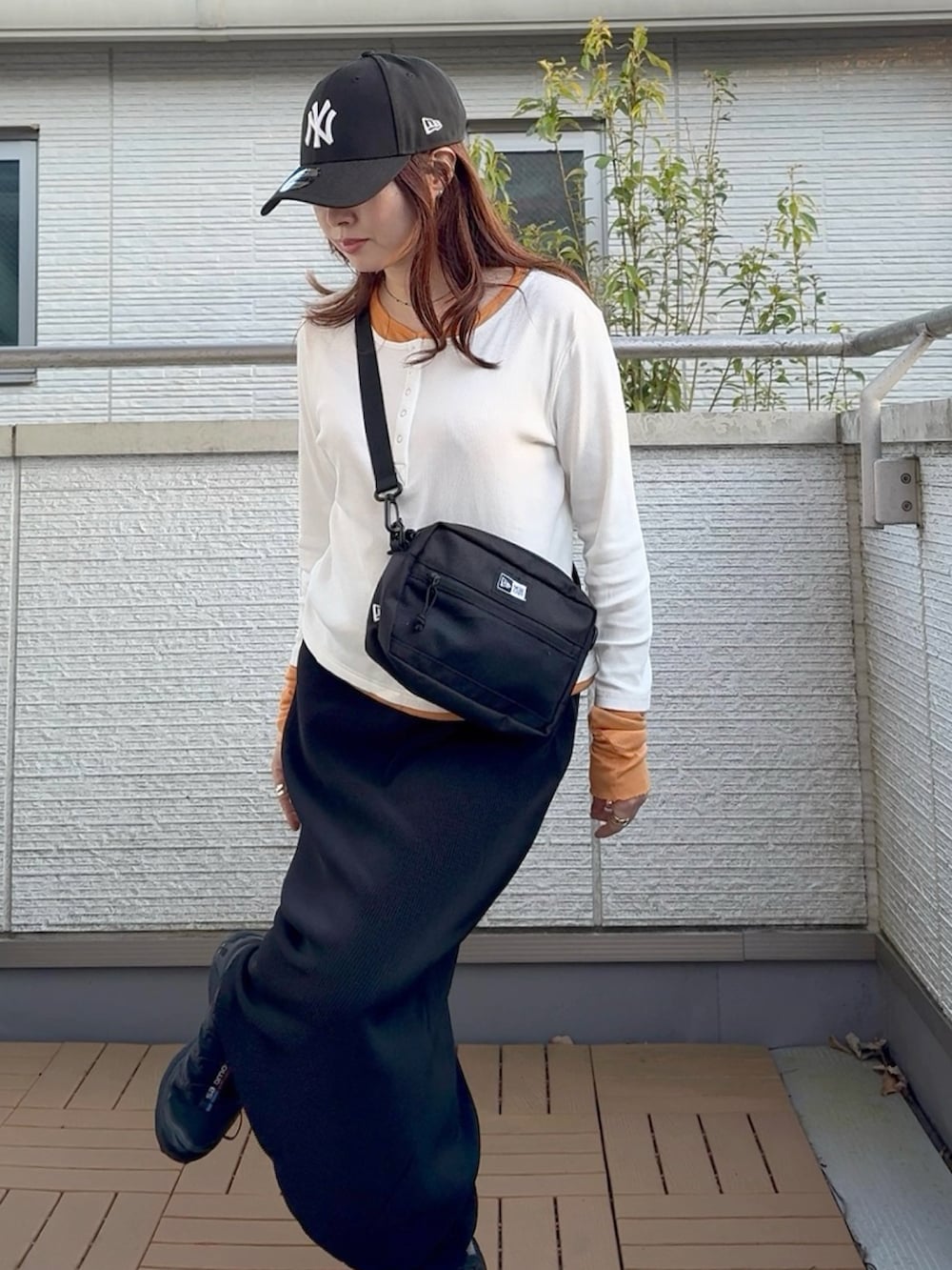 ブラック系のスカート、ホワイト系のTシャツ/カットソー、ブラック系のショルダーバッグを着用したレディースの春コーディネートの4枚目の写真