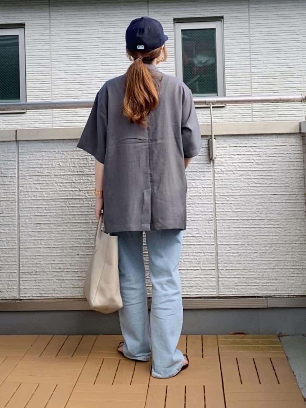 グレー系のテーラードジャケット、ホワイト系のタンクトップ、ブルー系のデニムパンツを着用したレディースの夏コーディネートの3枚目の写真