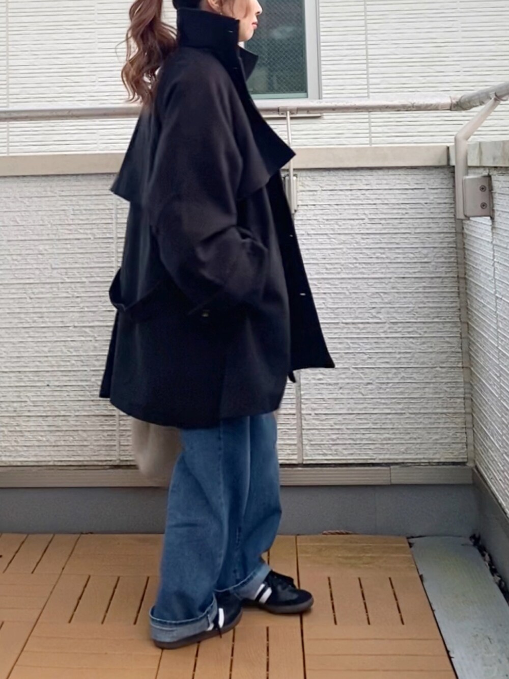 ブラック系のトレンチコート、グレー系のスウェット、ブルー系のデニムパンツを着用したレディースの秋コーディネートの3枚目の写真