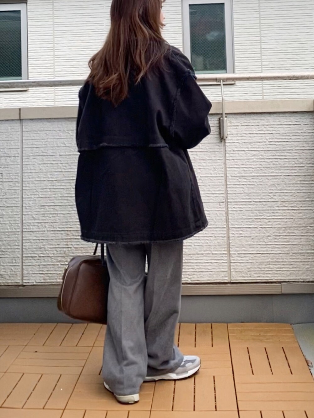 ブラック系のデニムジャケット、ブラック系のスウェット、グレー系のスラックスを着用したレディースの冬コーディネートの3枚目の写真