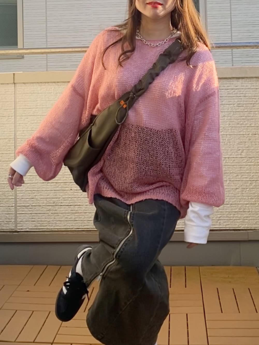 ピンク系のニット/セーター、ブラック系のスカート、グリーン系のショルダーバッグを着用したレディースの冬コーディネートの4枚目の写真