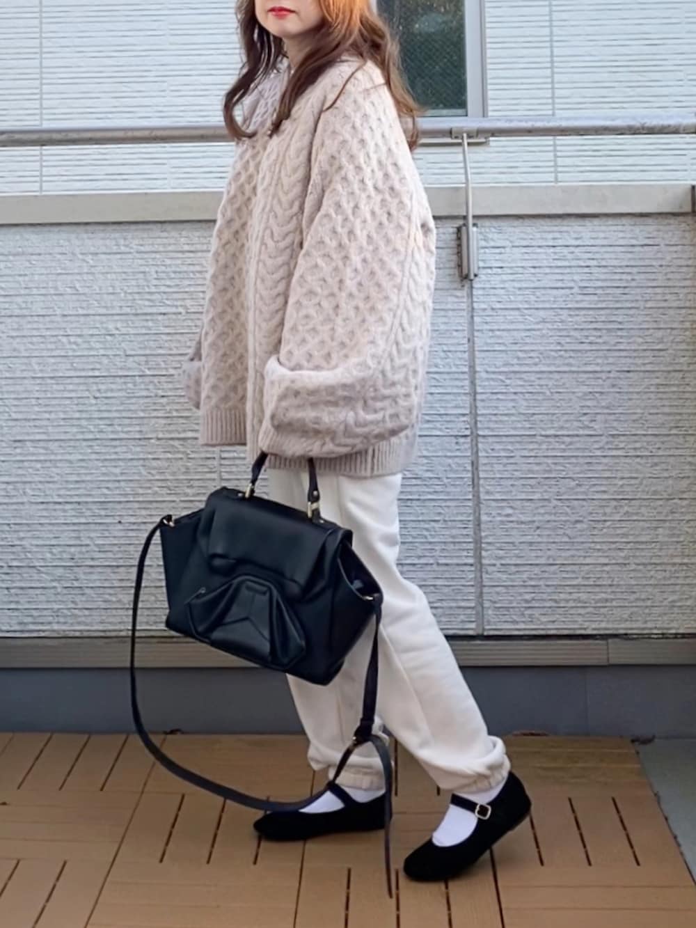 ベージュ系のニット/セーター、ホワイト系のパンツ、ブラック系のハンドバッグを着用したレディースの秋コーディネートの3枚目の写真