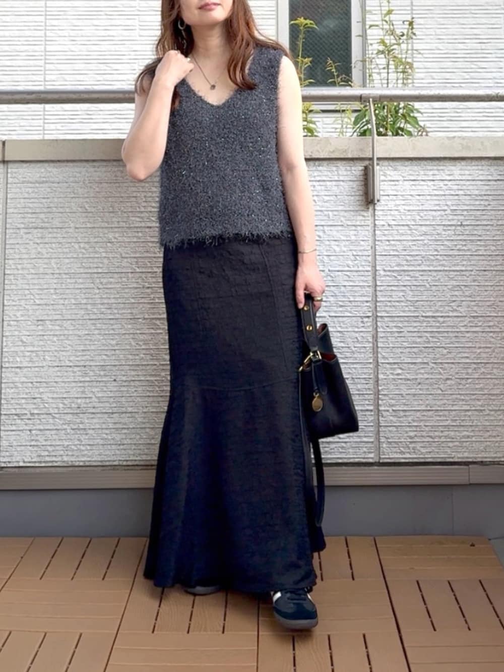 グレー系のベスト、ブラック系のワンピース、ブラック系のショルダーバッグを着用したレディースの夏コーディネートの2枚目の写真