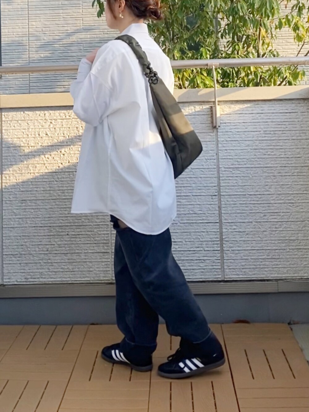 ホワイト系のシャツ/ブラウス、ブラック系のデニムパンツ、グリーン系のショルダーバッグを着用したレディースの春コーディネートの3枚目の写真