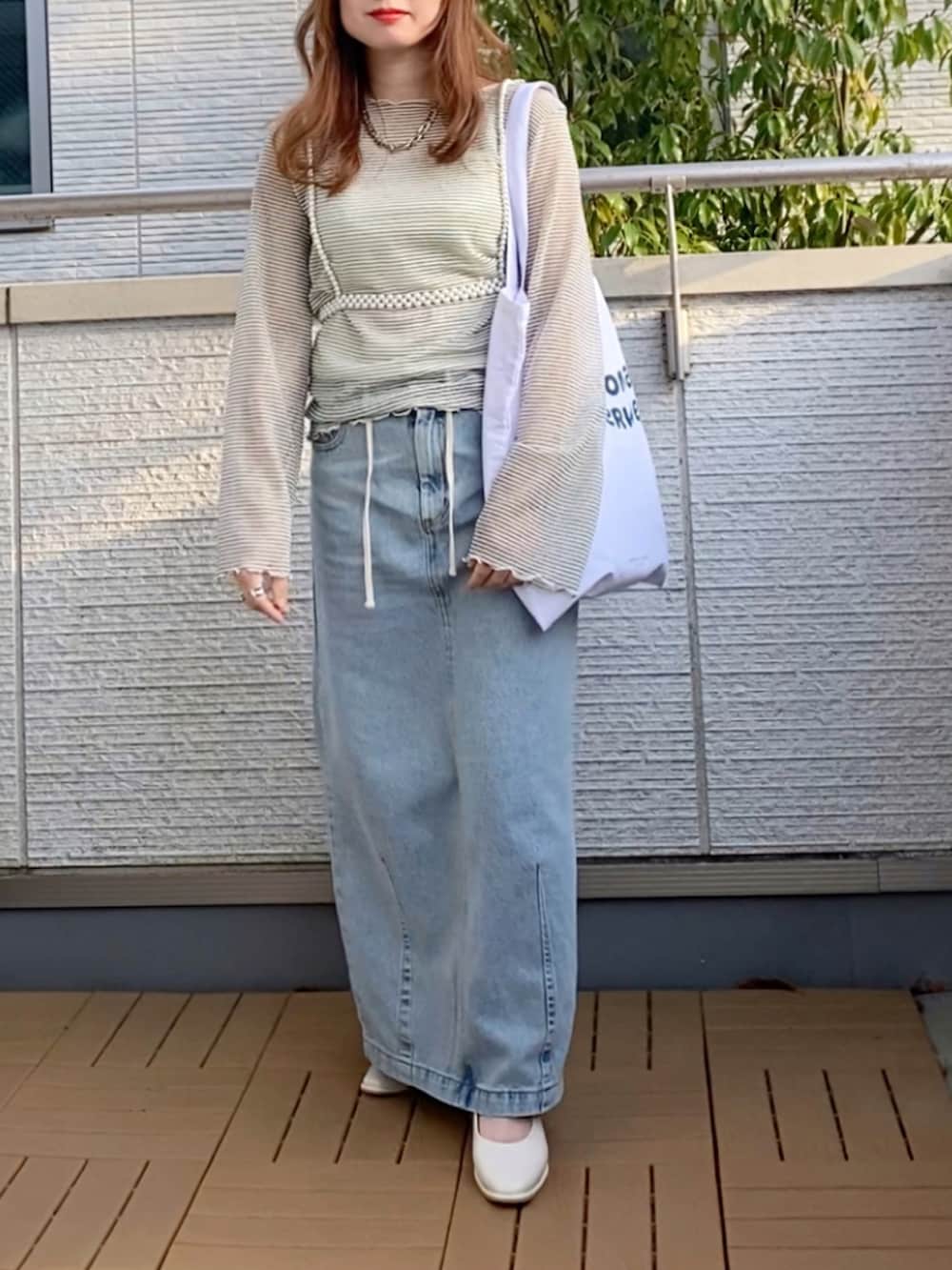 ホワイト系のTシャツ/カットソー、ブルー系のデニムスカート、ホワイト系のトートバッグを着用したレディースの春コーディネートの2枚目の写真