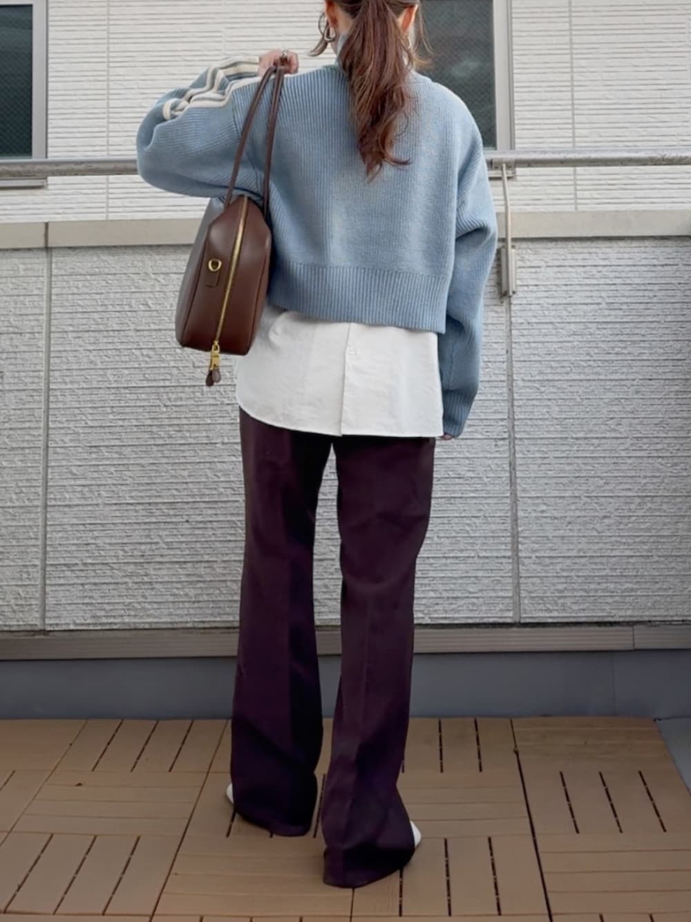 ブルー系のニット/セーター、ホワイト系のシャツ/ブラウス、ブラウン系のスラックスを着用したレディースの冬コーディネートの3枚目の写真