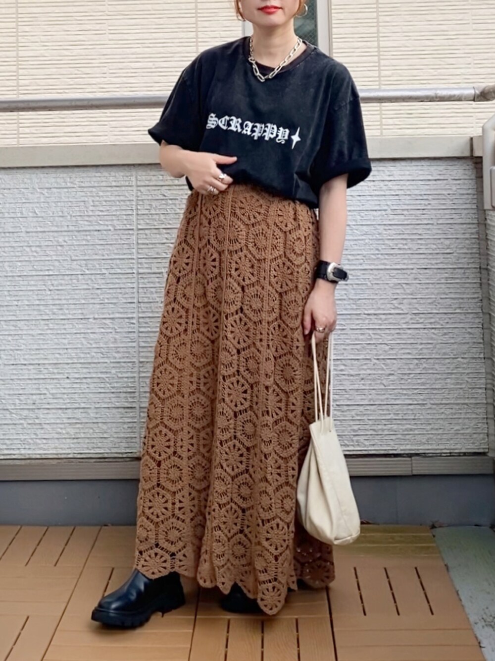 ブラック系のTシャツ/カットソー、ブラウン系のスカート、ブラック系のブーツを着用したレディースの秋コーディネートの2枚目の写真