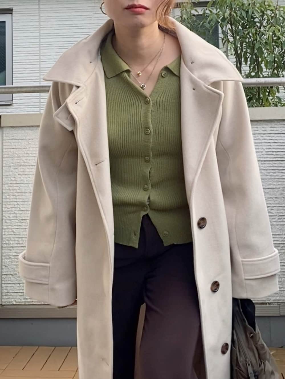 ホワイト系のステンカラーコート、グリーン系のカーディガン/ボレロ、ブラウン系のその他パンツを着用したレディースの冬コーディネートの2枚目の写真