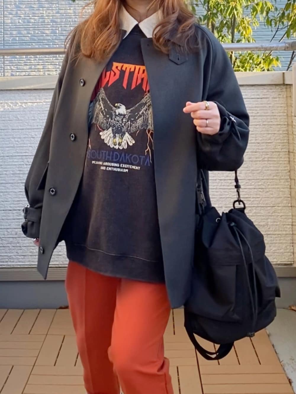 グレー系のブルゾン、グレー系のスウェット、オレンジ系のその他パンツを着用したレディースの冬コーディネートの4枚目の写真