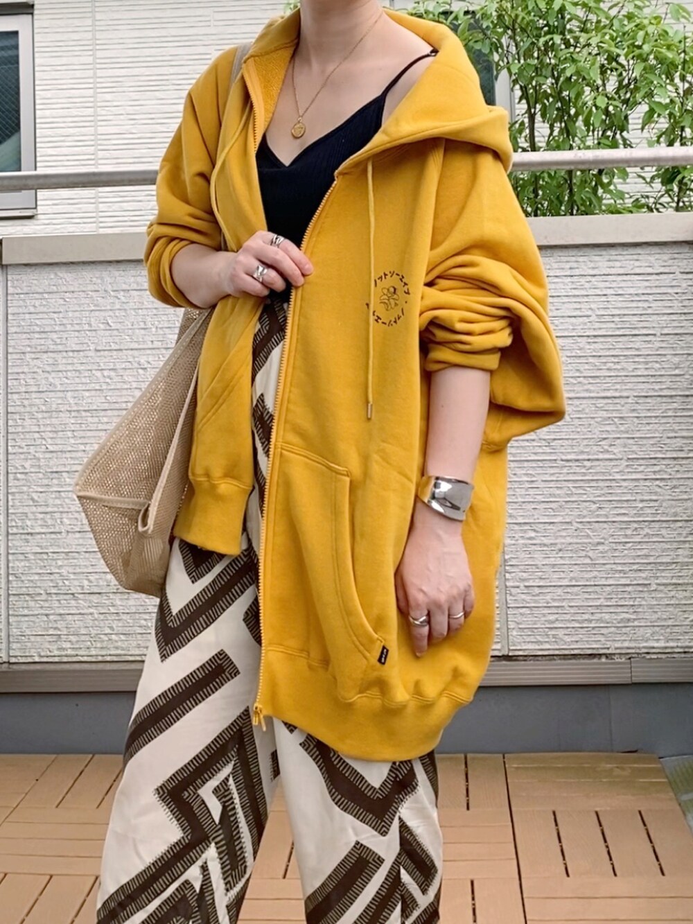 イエロー系のパーカーを着用したレディースの夏コーディネートの2枚目の写真