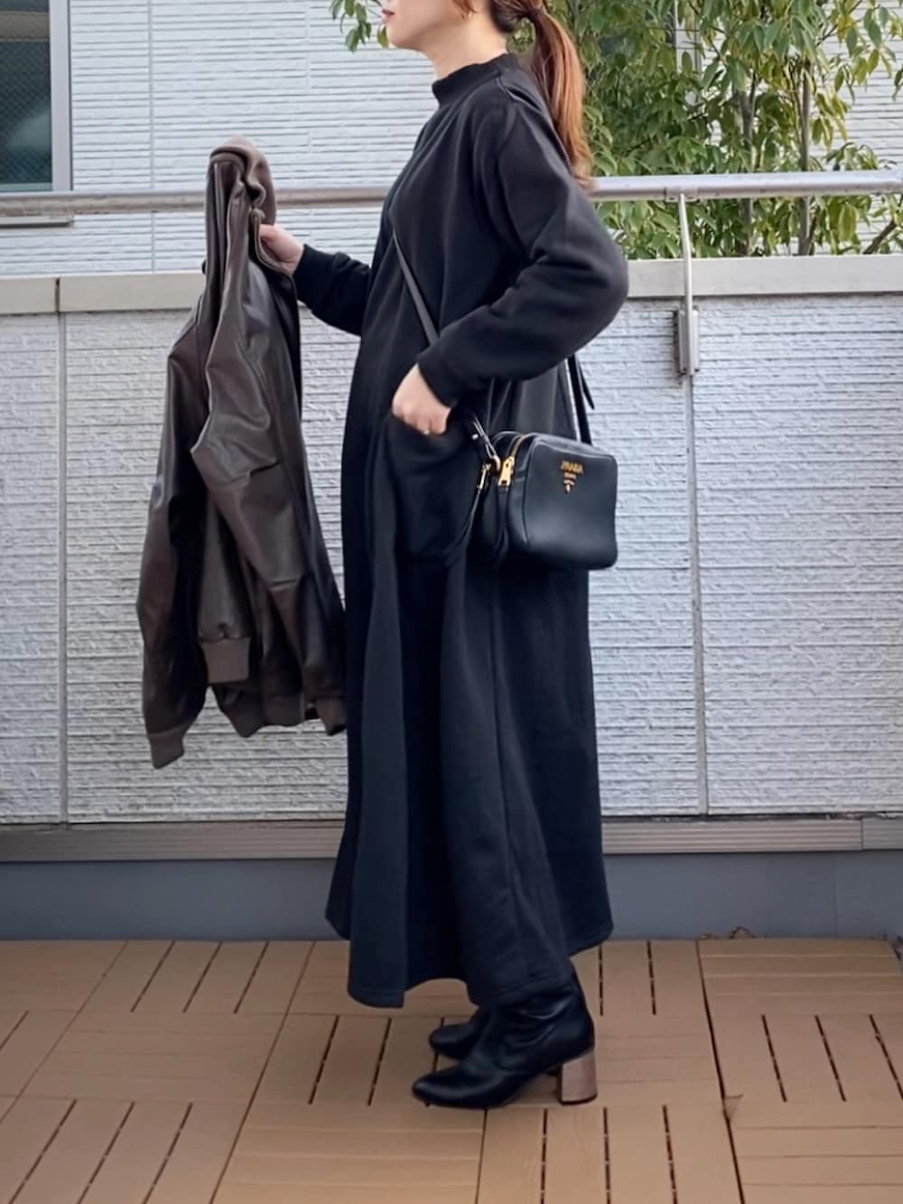 ブラック系のワンピース、ブラウン系のライダースジャケット、ブラック系のブーツを着用したレディースの冬コーディネートの4枚目の写真