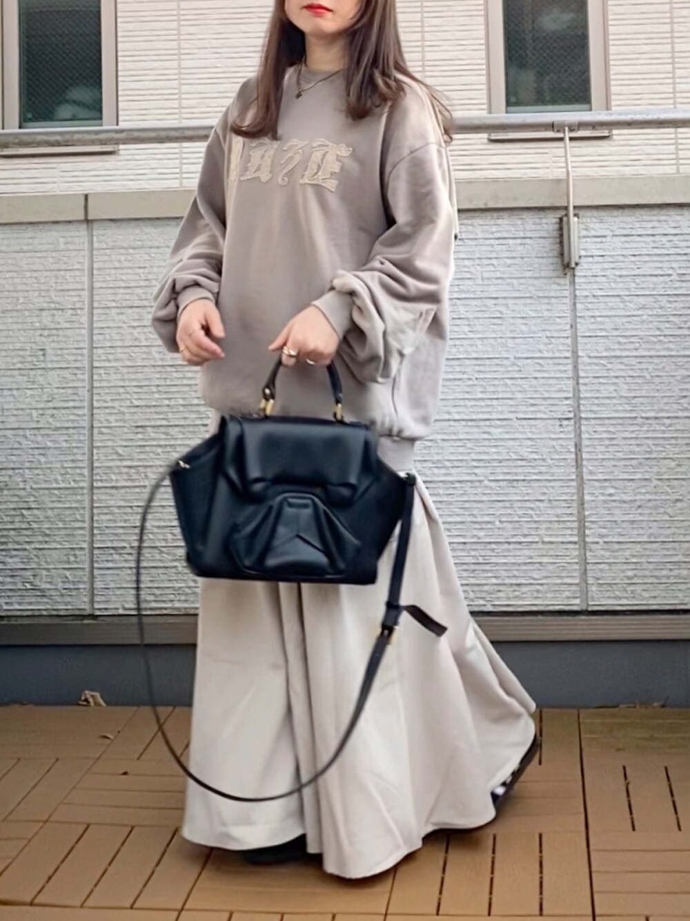 ベージュ系のトップス、ホワイト系のスカート、ブラック系のハンドバッグを着用したレディースの冬コーディネートの2枚目の写真