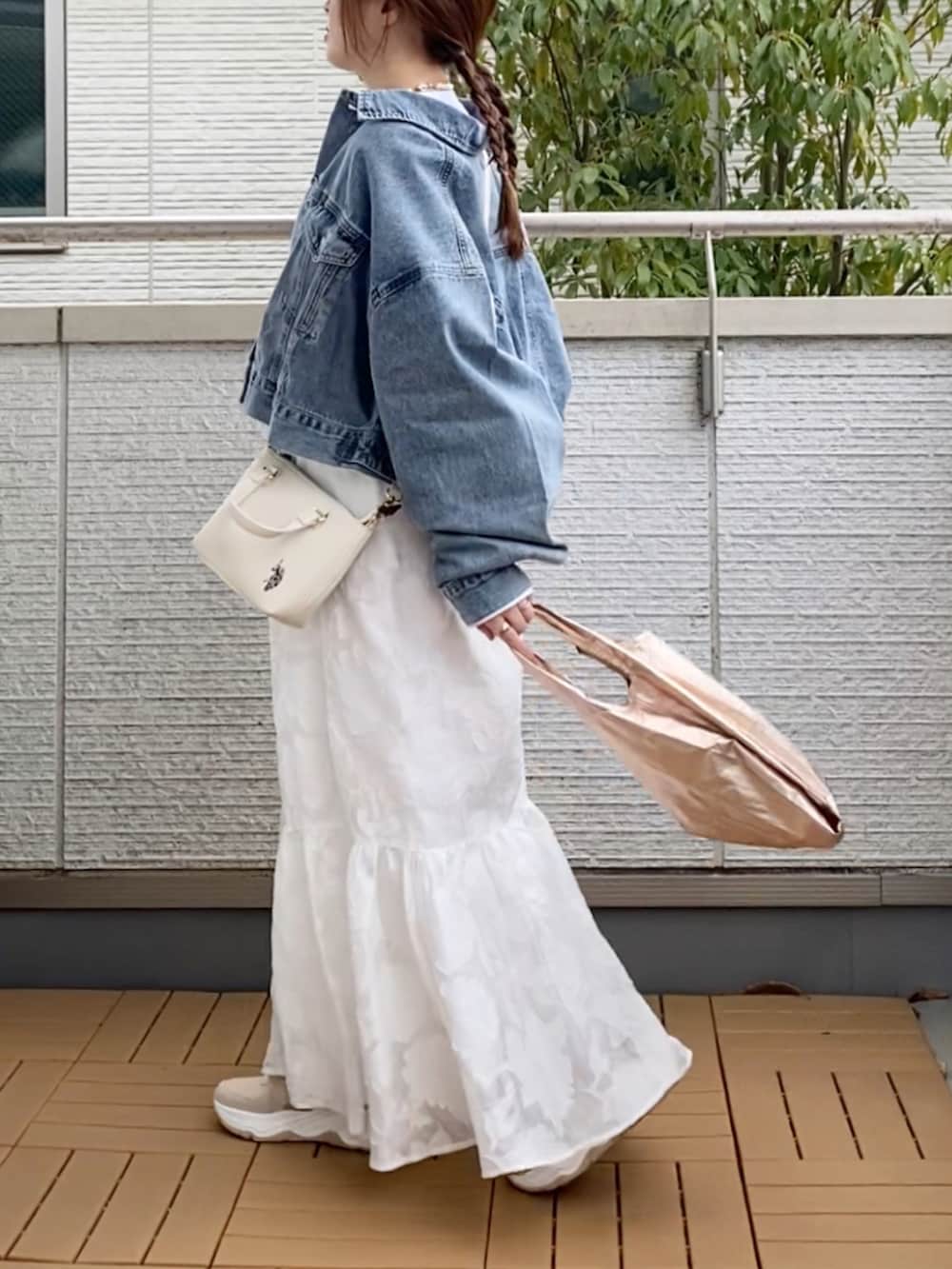 ブルー系のデニムジャケット、ホワイト系のスカート、ホワイト系のショルダーバッグを着用したレディースの春コーディネートの3枚目の写真