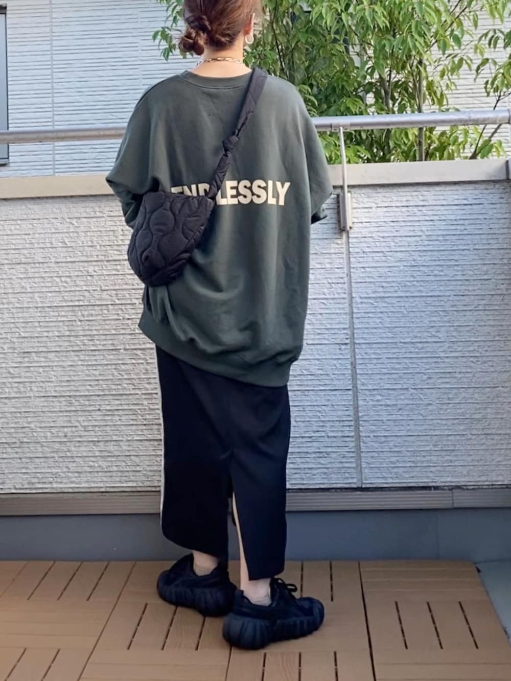 グリーン系のスウェット、ブラック系のスカート、ブラック系のショルダーバッグを着用したレディースの秋コーディネートの2枚目の写真