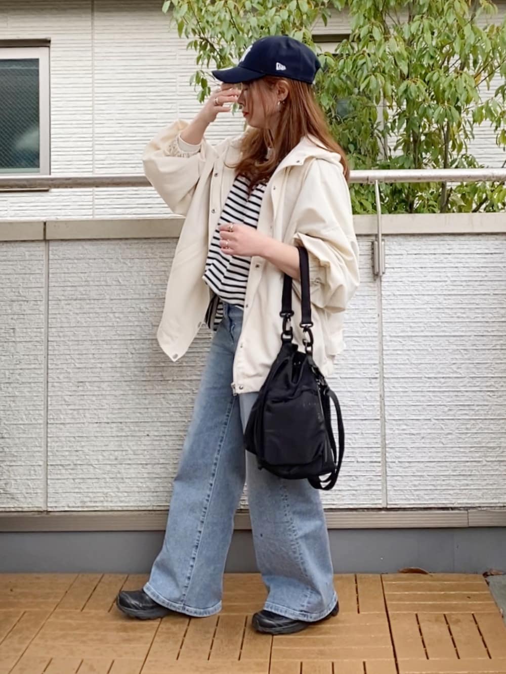 ホワイト系のマウンテンパーカー、ブラック系のTシャツ/カットソー、ブルー系のデニムパンツを着用したレディースの春コーディネートの2枚目の写真