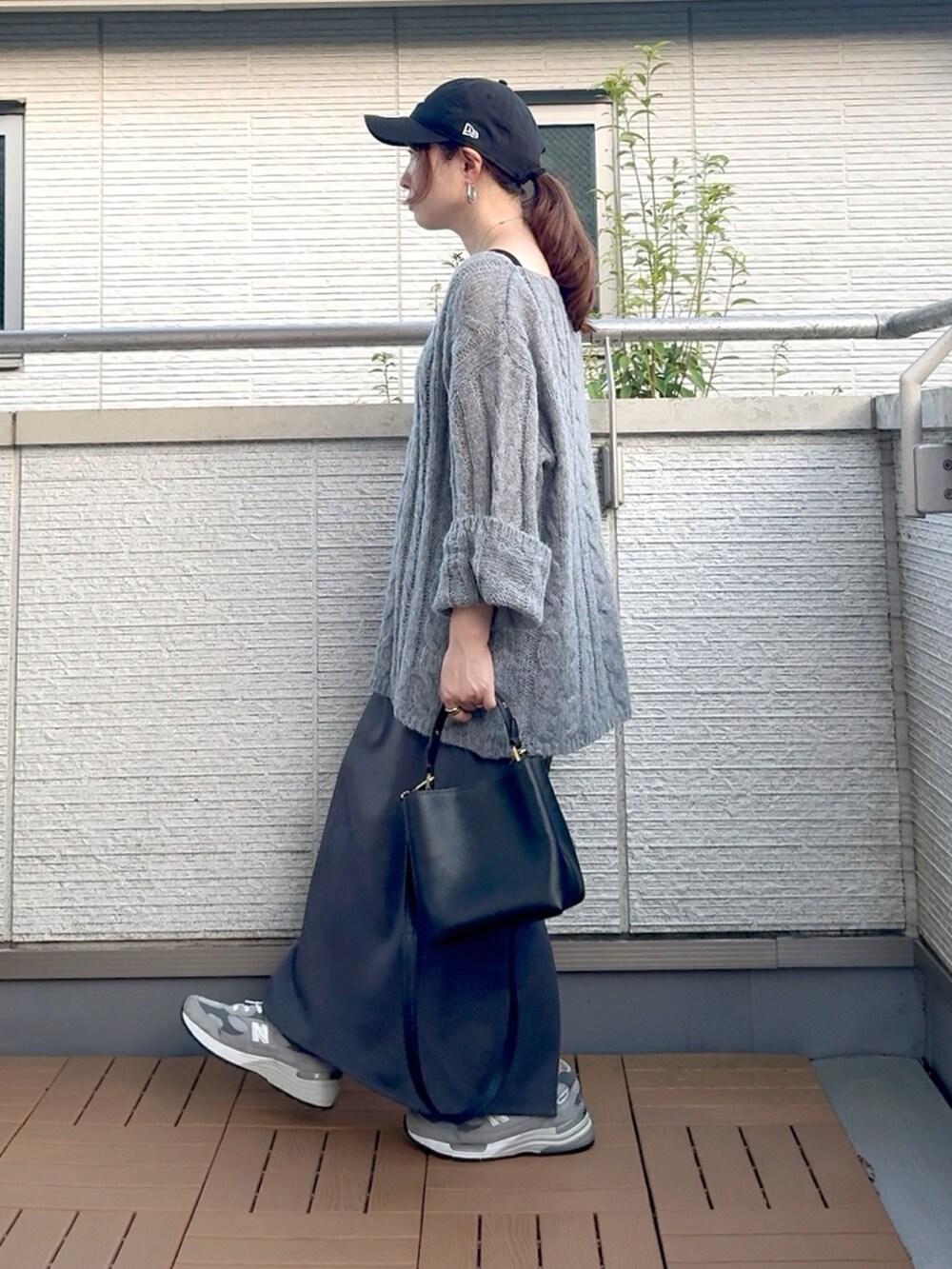 グレー系のニット/セーター、ブラック系のショルダーバッグ、グレー系のスカートを着用したレディースの夏コーディネートの3枚目の写真