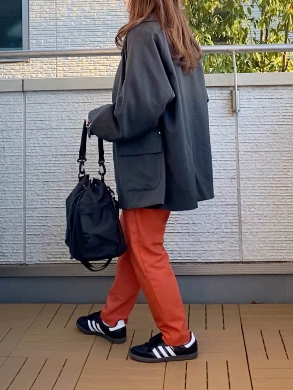グレー系のブルゾン、グレー系のスウェット、オレンジ系のその他パンツを着用したレディースの冬コーディネートの3枚目の写真