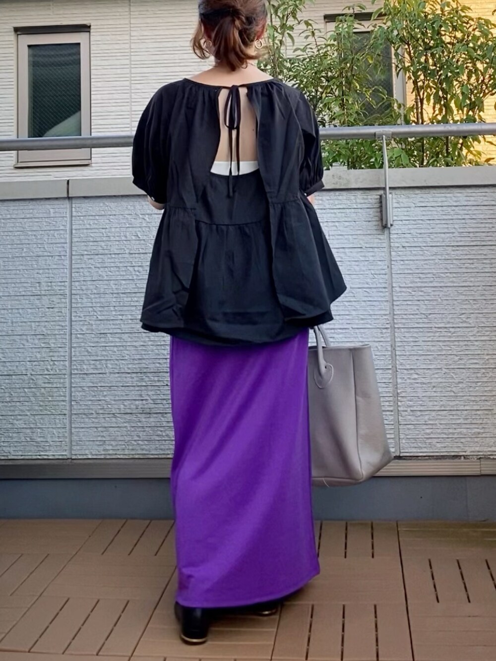 ブラック系のシャツ/ブラウス、パープル系のスカート、ベージュ系のトートバッグを着用したレディースの夏コーディネートの3枚目の写真