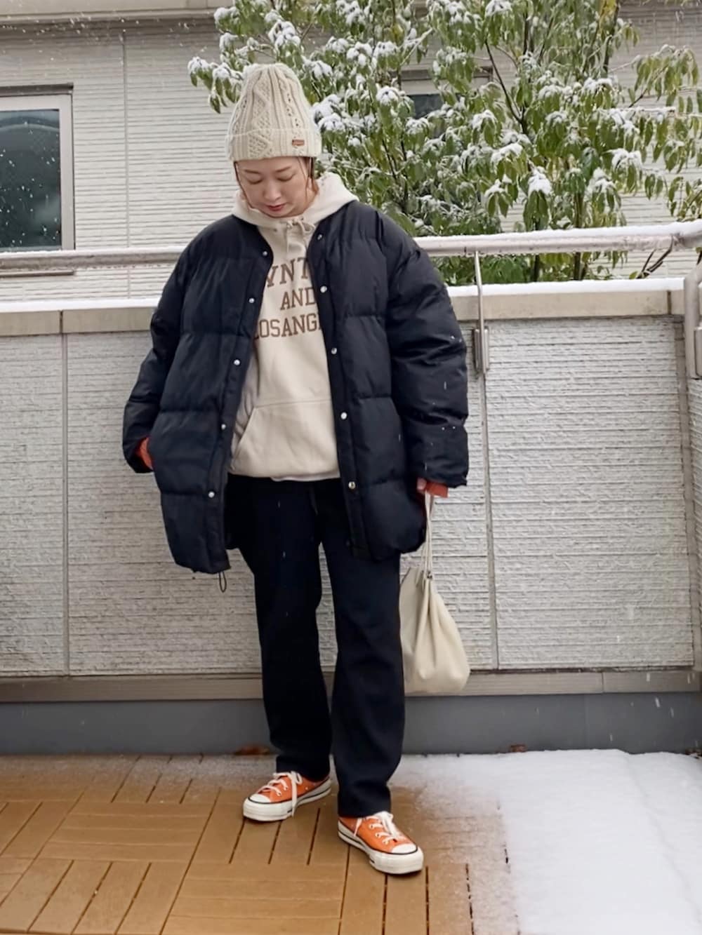 ブラック系のダウンジャケット/コート、ブラック系のその他パンツ、オレンジ系のスニーカーを着用したレディースの冬コーディネートの2枚目の写真
