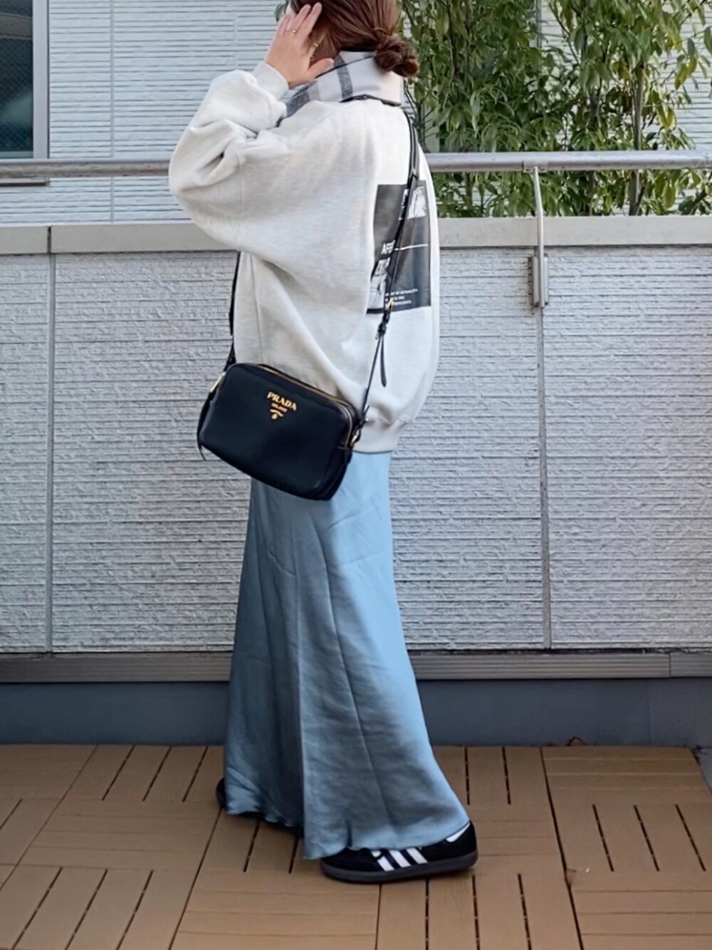 グレー系のスウェット、ブルー系のスカート、ブラック系のスニーカーを着用したレディースの冬コーディネートの2枚目の写真