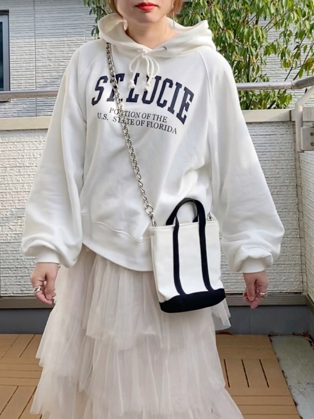 ホワイト系のパーカー、ホワイト系のスカート、グレー系のスニーカーを着用したレディースの春コーディネートの4枚目の写真